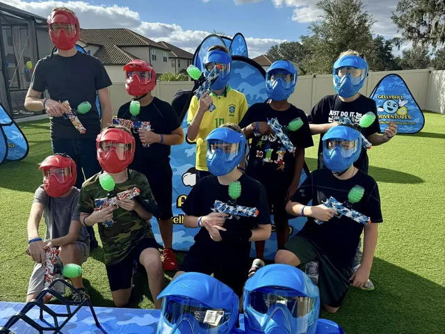 A masked team poses with gear and pop-up bunkers at a backyard gellyball party