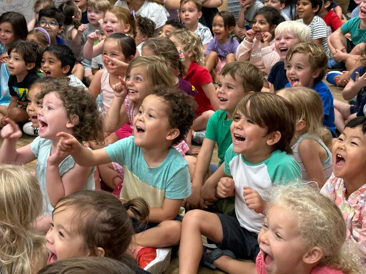 A seated audience of kids reacting to a show