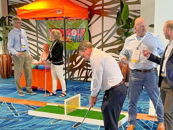 Adults playing portable mini golf indoors