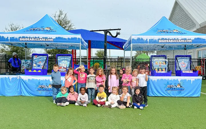 A group of kids in front of snow tents and carnival games at an outdoor event