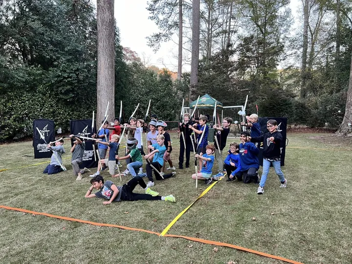 A group of kids in masks pose with bows on a field