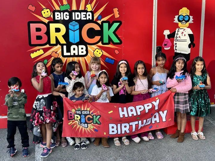 Kids at a birthday party hold up the brick builds they made
