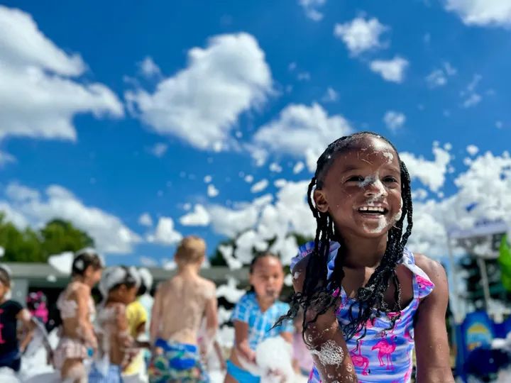 A girl laughs in a field of foam under a blue sky