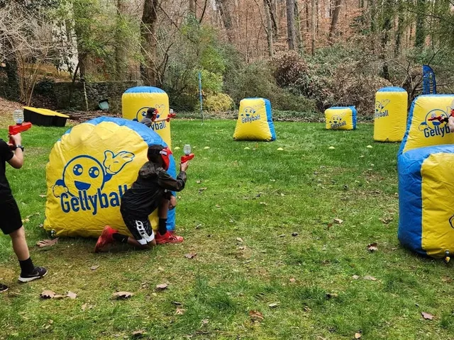 Kids play gellyball behind inflatable bunkers on a lawn