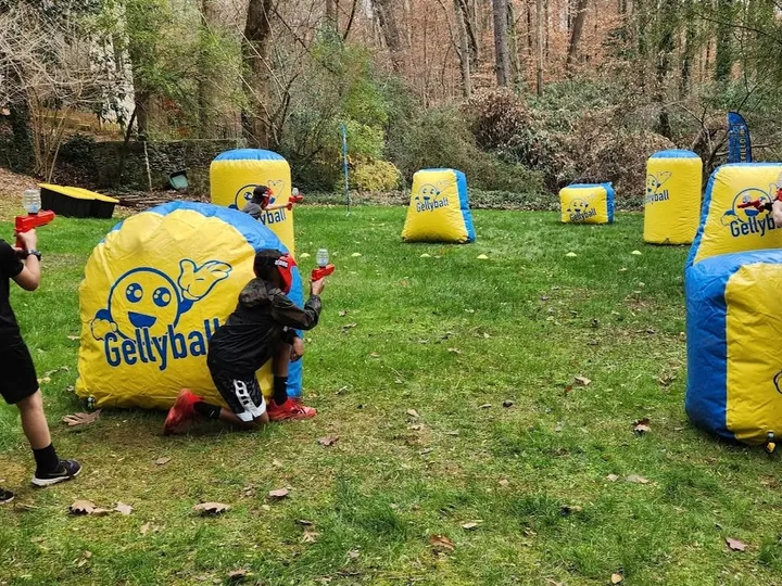 Kids play gellyball behind inflatable bunkers on a lawn