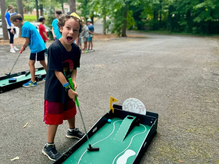 A kid cheers after sinking a putt on a portable mini golf hole